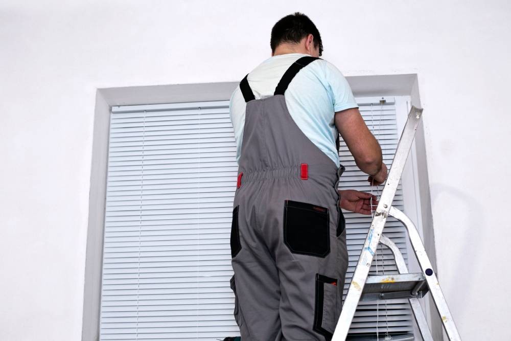 A Hunter Douglas Certified window treatment repair person inspecting blinds near Spokane, Washington (WA)